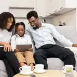 Family sitting on the couch with a tablet and their dog, discussing “Is a pet right for me?” and the realities of pet ownership.