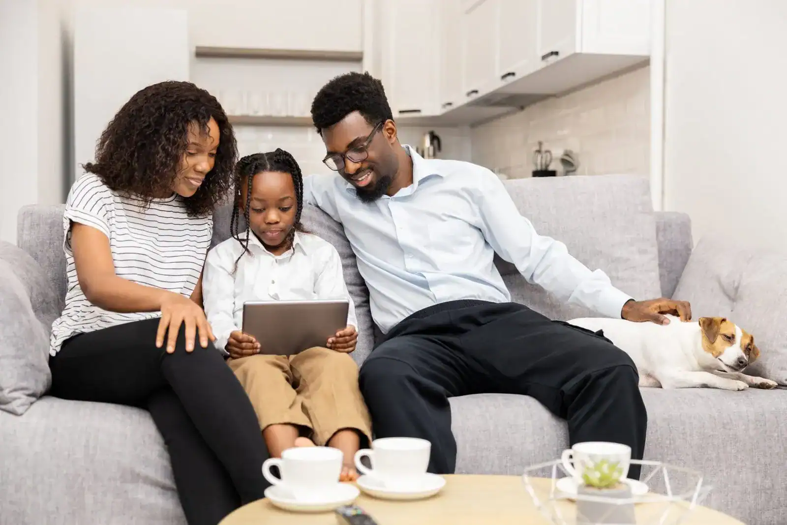 Family sitting on the couch with a tablet and their dog, discussing “Is a pet right for me?” and the realities of pet ownership.